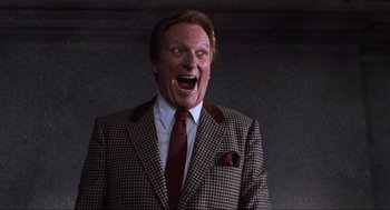 Movie still from “Beetlejuice” (1988), directed by Tim Burton – A man wearing a suit and tie with his mouth wide open; Medium shot, Low angle