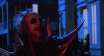 Movie still from “Beetlejuice” (1988), directed by Tim Burton – A person holding a knife; Medium shot, Low angle