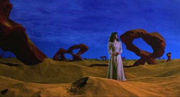 Movie still from “Beetlejuice” (1988), directed by Tim Burton – A woman in a white dress standing in the desert; Wide shot, Low angle