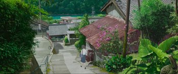 Movie still from “Belle” (2021), directed by Mamoru Hosoda – A person walking down a street near some buildings; Extreme Wide shot, High angle