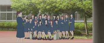 Movie still from “Belle” (2021), directed by Mamoru Hosoda – A group of women in school uniforms sitting on a bench; Extreme Wide shot, High angle