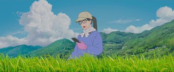 Movie still from “Belle” (2021), directed by Mamoru Hosoda – A woman is sitting in the grass looking at her cell phone; Medium shot, Low angle