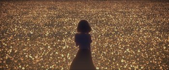 Movie still from “Belle” (2021), directed by Mamoru Hosoda – A woman standing in front of a field filled with lights at night; Extreme Wide shot, High angle
