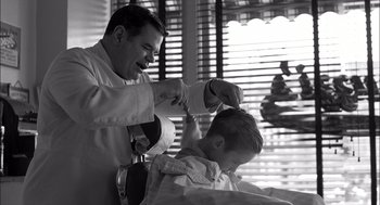 Movie still from “The Man Who Wasn't There” (2001), directed by Joel Coen – A man cutting a young boy's hair in a barber shop; Medium shot, Over the shoulder angle