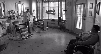 Movie still from “The Man Who Wasn't There” (2001), directed by Joel Coen – An old photo of a barber shop with a barber chair; Wide shot, High angle