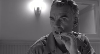 Movie still from “The Man Who Wasn't There” (2001), directed by Joel Coen – Black and white photograph of a man eating a piece of food; Close Up shot, Low angle
