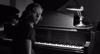 Movie still from “The Man Who Wasn't There” (2001), directed by Joel Coen – A young girl standing in front of an upright piano; Close Up shot, Low angle