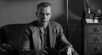 Movie still from “The Man Who Wasn't There” (2001), directed by Joel Coen – Black and white photograph of a man smoking a cigarette; Close Up shot, Low angle
