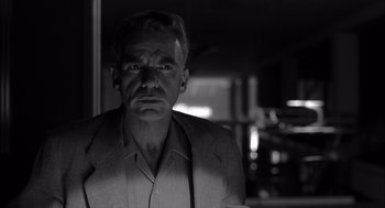 Movie still from “The Man Who Wasn't There” (2001), directed by Joel Coen – Black and white photograph of a man in a suit; Close Up shot, Low angle