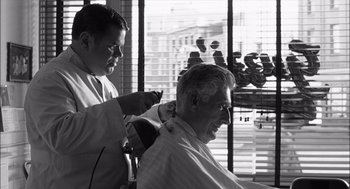 Movie still from “The Man Who Wasn't There” (2001), directed by Joel Coen – A man getting his hair cut by a barber; Medium shot, Over the shoulder angle