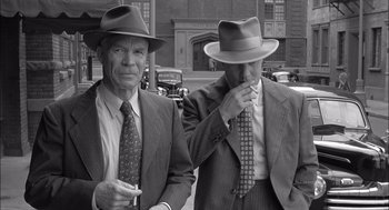 Movie still from “The Man Who Wasn't There” (2001), directed by Joel Coen – A couple of men standing next to each other on a street; Medium shot, High angle