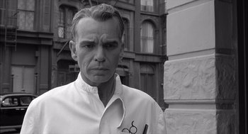 Movie still from “The Man Who Wasn't There” (2001), directed by Joel Coen – A black and white photo of a man with a pair of scissors in his mouth; Close Up shot, Low angle