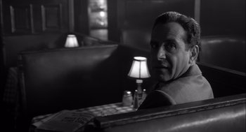 Movie still from “The Man Who Wasn't There” (2001), directed by Joel Coen – A black and white photo of a man sitting in a booth; Close Up shot, Over the shoulder angle