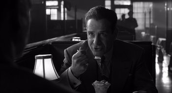 Movie still from “The Man Who Wasn't There” (2001), directed by Joel Coen – A black and white photo of a man in a suit and tie eating; Close Up shot, Over the shoulder angle