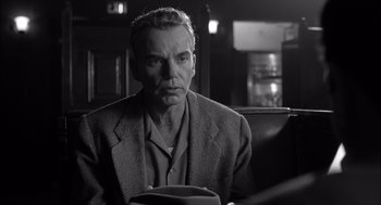 Movie still from “The Man Who Wasn't There” (2001), directed by Joel Coen – Black and white photograph of a man sitting in a chair; Close Up shot, Over the shoulder angle