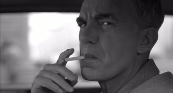 Movie still from “The Man Who Wasn't There” (2001), directed by Joel Coen – A black and white photo of a man smoking a cigarette; Close Up shot, Low angle
