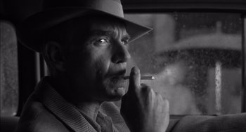 Movie still from “The Man Who Wasn't There” (2001), directed by Joel Coen – A black and white photo of a man smoking a cigarette; Close Up shot, Low angle