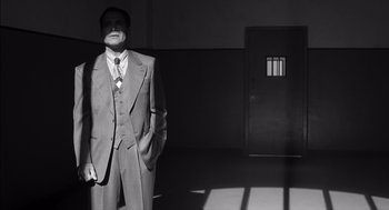 Movie still from “The Man Who Wasn't There” (2001), directed by Joel Coen – A black and white photo of a man in a suit and tie; Medium shot, Low angle