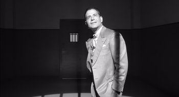 Movie still from “The Man Who Wasn't There” (2001), directed by Joel Coen – Black and white photograph of a man in a suit and tie; Medium shot, Low angle