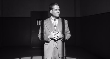 Movie still from “The Man Who Wasn't There” (2001), directed by Joel Coen – A black and white photo of a man in a suit and tie; Medium shot, Low angle