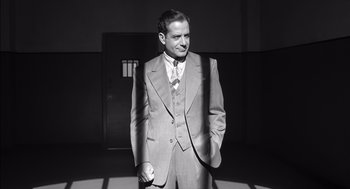 Movie still from “The Man Who Wasn't There” (2001), directed by Joel Coen – A black and white photo of a man in a suit and tie; Medium shot, Low angle