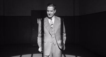 Movie still from “The Man Who Wasn't There” (2001), directed by Joel Coen – A black and white photo of a man in a suit and tie; Medium shot, Low angle