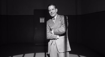 Movie still from “The Man Who Wasn't There” (2001), directed by Joel Coen – A man in a suit standing in front of a door; Medium shot, Low angle