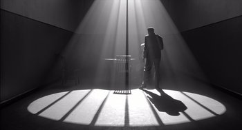 Movie still from “The Man Who Wasn't There” (2001), directed by Joel Coen – A man standing on a stage in the sunlight; Wide shot, Low angle