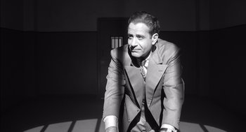 Movie still from “The Man Who Wasn't There” (2001), directed by Joel Coen – A black and white photo of a man in a suit and tie; Medium shot, High angle