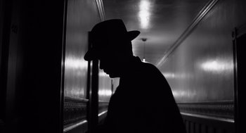 Movie still from “The Man Who Wasn't There” (2001), directed by Joel Coen – A man wearing a hat standing next to a wall; Close Up shot, Low angle
