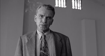 Movie still from “The Man Who Wasn't There” (2001), directed by Joel Coen – A man in a suit and tie smoking a cigarette; Close Up shot, Low angle