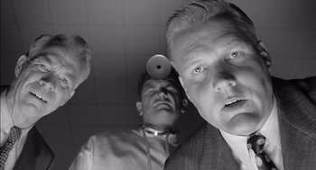 Movie still from “The Man Who Wasn't There” (2001), directed by Joel Coen – A black - and - white photo of three men in suits and ties; Close Up shot, Low angle