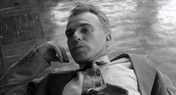 Movie still from “The Man Who Wasn't There” (2001), directed by Joel Coen – Black and white photograph of a man wearing a suit and tie; Close Up shot, Low angle