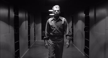 Movie still from “The Man Who Wasn't There” (2001), directed by Joel Coen – A black and white photo of a man walking in a hallway; Medium shot, Low angle