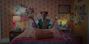 Movie still from “Better Nate Than Ever” (2022), directed by Tim Federle – A person sitting on a bed holding a coffee cup; Medium shot, High angle