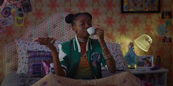 Movie still from “Better Nate Than Ever” (2022), directed by Tim Federle – A woman sitting on a bed drinking a cup of coffee; Medium shot, Over the shoulder angle