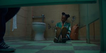 Movie still from “Better Nate Than Ever” (2022), directed by Tim Federle – A person sitting on the ground in a bathroom; Wide shot, Overhead angle