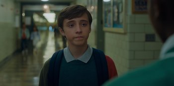 Movie still from “Better Nate Than Ever” (2022), directed by Tim Federle – A young man in a green shirt is standing in a hallway; Close Up shot, Over the shoulder angle