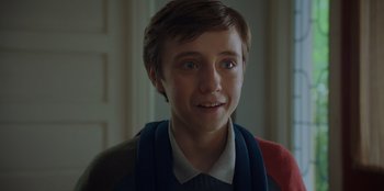 Movie still from “Better Nate Than Ever” (2022), directed by Tim Federle – A young boy with a sweater around his neck; Close Up shot, Over the shoulder angle