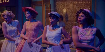 Movie still from “Better Nate Than Ever” (2022), directed by Tim Federle – A group of women standing next to each other holding papers; Medium shot, Low angle