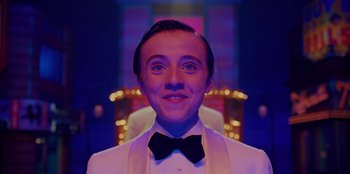 Movie still from “Better Nate Than Ever” (2022), directed by Tim Federle – A person wearing a suit and bow tie; Close Up shot, Low angle