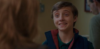 Movie still from “Better Nate Than Ever” (2022), directed by Tim Federle – A young man smiling at the camera while wearing a vest; Close Up shot, Over the shoulder angle