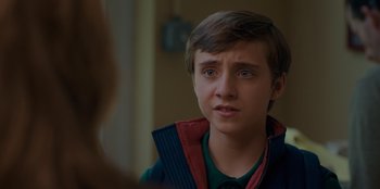 Movie still from “Better Nate Than Ever” (2022), directed by Tim Federle – A young man looking at the camera while wearing a vest; Close Up shot, Over the shoulder angle