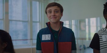 Movie still from “Better Nate Than Ever” (2022), directed by Tim Federle – A young man wearing a vest with the number 1 3 on it; Close Up shot, Over the shoulder angle
