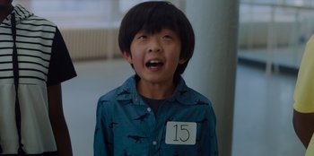 Movie still from “Better Nate Than Ever” (2022), directed by Tim Federle – A young boy wearing a blue shirt with a number 1 5 on it; Close Up shot, High angle