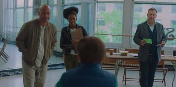 Movie still from “Better Nate Than Ever” (2022), directed by Tim Federle – A woman standing next to a man in front of a table; Medium shot, Over the shoulder angle