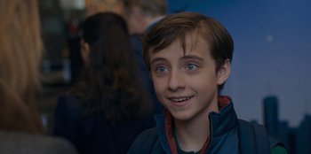 Movie still from “Better Nate Than Ever” (2022), directed by Tim Federle – A young boy with blue eyes smiling for the camera; Close Up shot, Over the shoulder angle