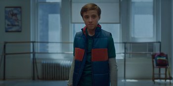 Movie still from “Better Nate Than Ever” (2022), directed by Tim Federle – A young boy wearing a blue and red vest; Medium shot, Low angle