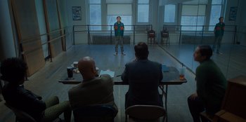 Movie still from “Better Nate Than Ever” (2022), directed by Tim Federle – A man standing in front of two other men in a room; Wide shot, Over the shoulder angle