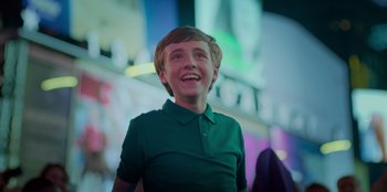 Movie still from “Better Nate Than Ever” (2022), directed by Tim Federle – A young boy in a green shirt smiling for the camera; Medium shot, Low angle